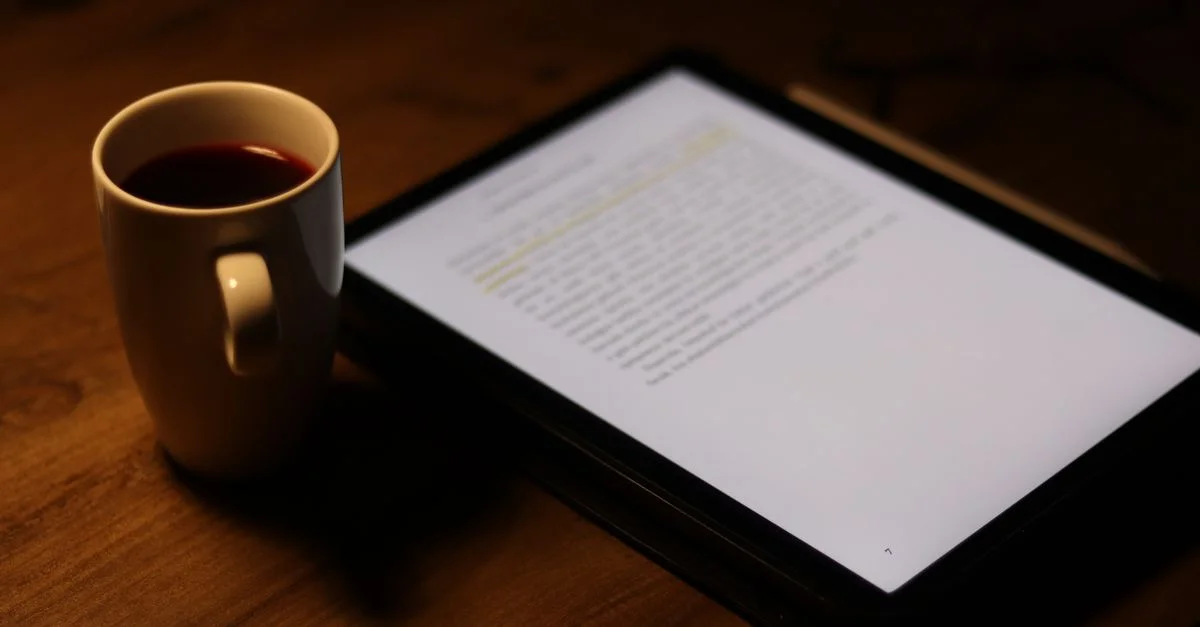 Tablette avec texte à côté d'une tasse de café sur une table en bois.