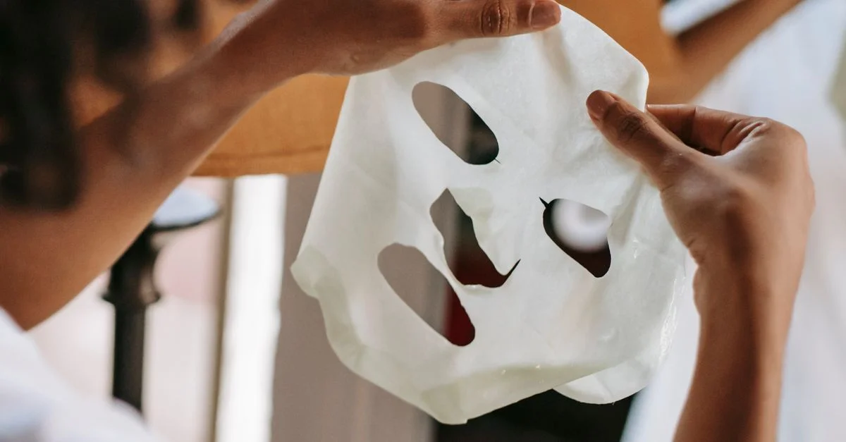 Gros plan sur l'application d'un masque en feuille hydratant dans le cadre d'une routine de soins de la peau.